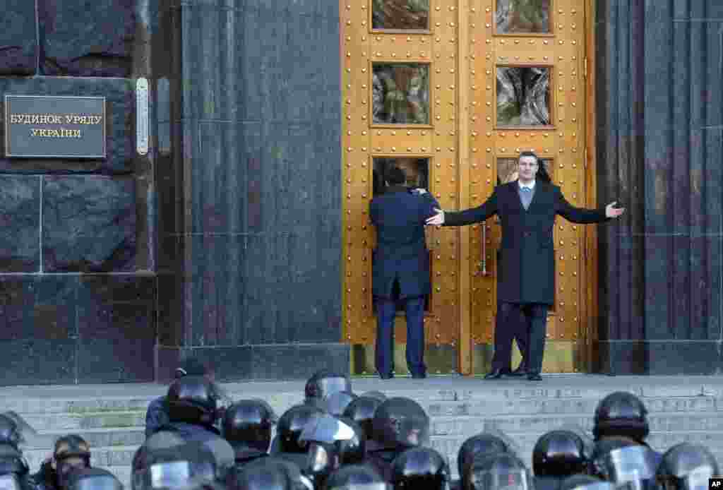 Vitali Klitschko, WBC heavyweight boxing champion and chairman of the Ukrainian opposition party Udar, raises his arms as he and another opposition leader, Oleh Tyahnybok, try to gain entry to the Cabinet of Ministers in Kyiv, Nov. 27, 2013.