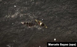 FILE – Fishermen are shown amid floating garbage in Guanabara Bay, where the sailing competitions at the 2016 Rio Olympic Games will be held, in Rio de Janeiro, Brazil, May 21, 2016.