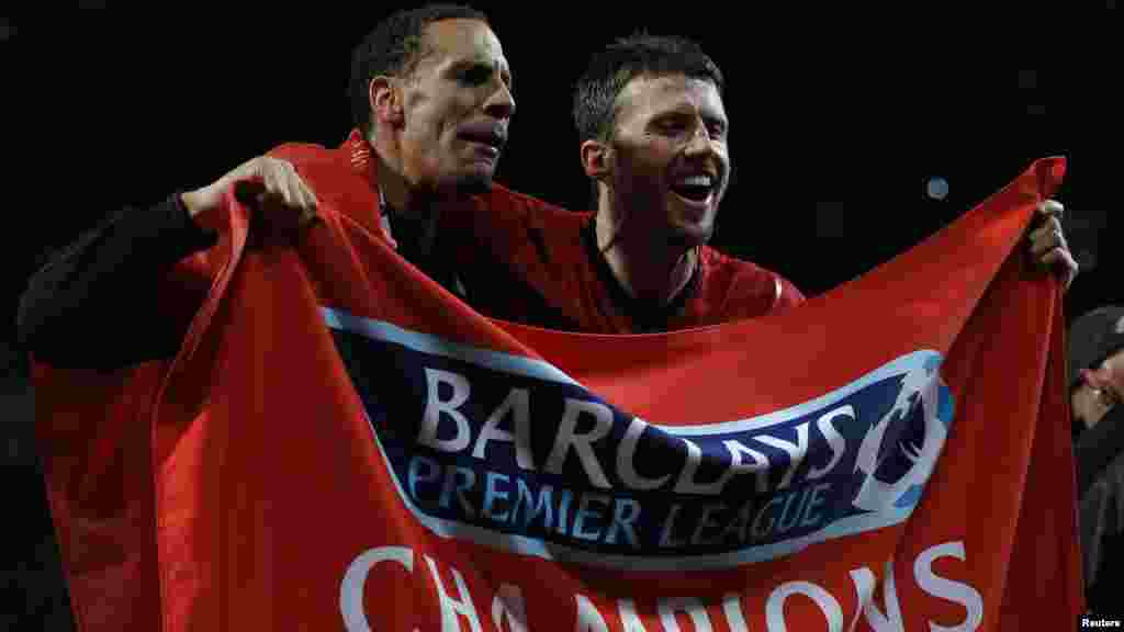 Manchester United&#39;s Rio Ferdinand (L) and Michael Carrick celebrate after they clinched the English Premier League soccer title with a win against Aston Villa at Old Trafford in Manchester. northern England, April 22, 2013.