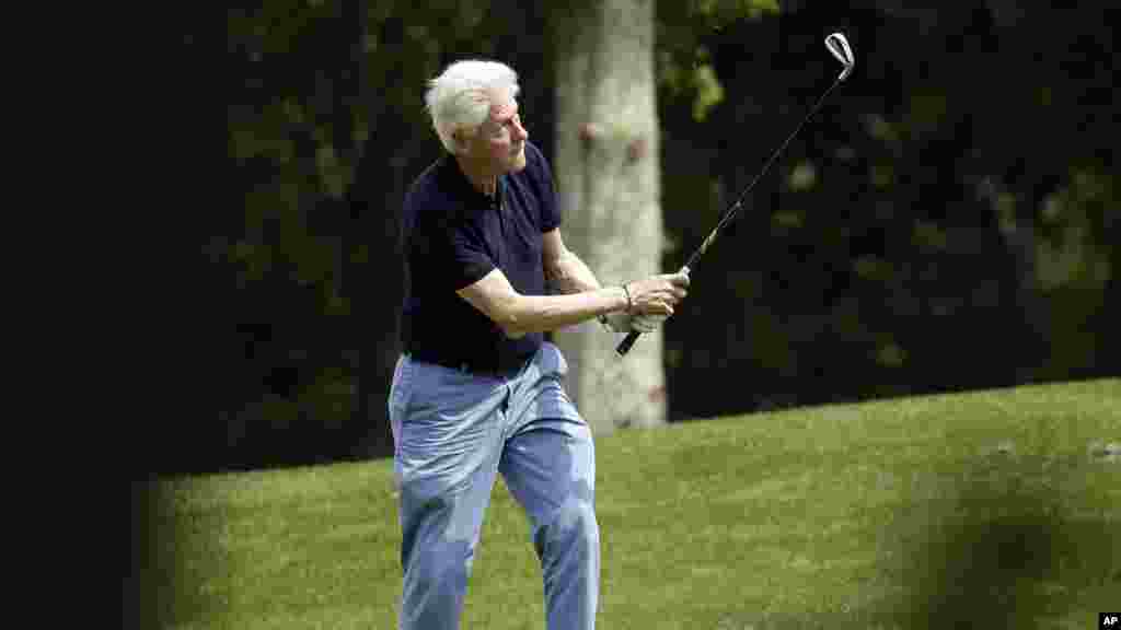 L'ancien chef d'état Bill Clinton suit de son regard une balle qu'il vient de frapper avec une crosse,15 août 2015.