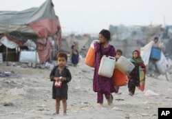 19일 파키스탄 라호르의 빈민가에서 아프간 출신 난민들이 물통을 들고 가고 있다.