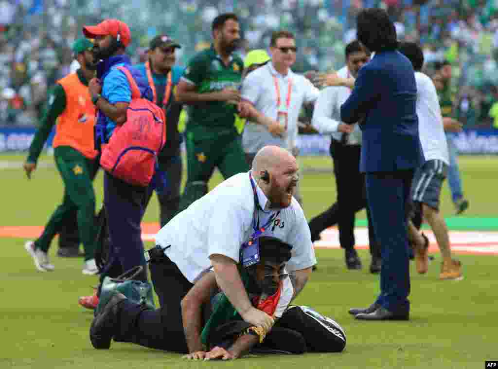 A security official stops a pitch invader after the 2019 Cricket World Cup group stage match between Pakistan and Afghanistan at Headingley in Leeds, northern England, June 29, 2019.