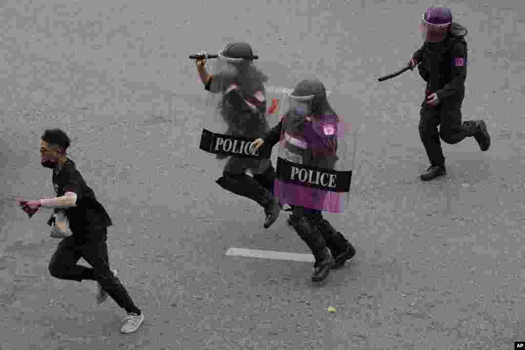 Riot police run after an anti-government protester during protests in Bangkok, Thailand.
