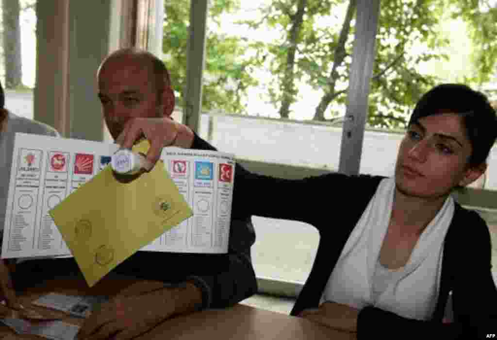 A polling station official hands over a ballot paper and a stamp at a polling station in Ankara, Turkey, June 12, 2011