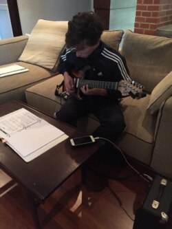El hijo de María practica guitarra durante la cuarentena. Foto: Cortesía