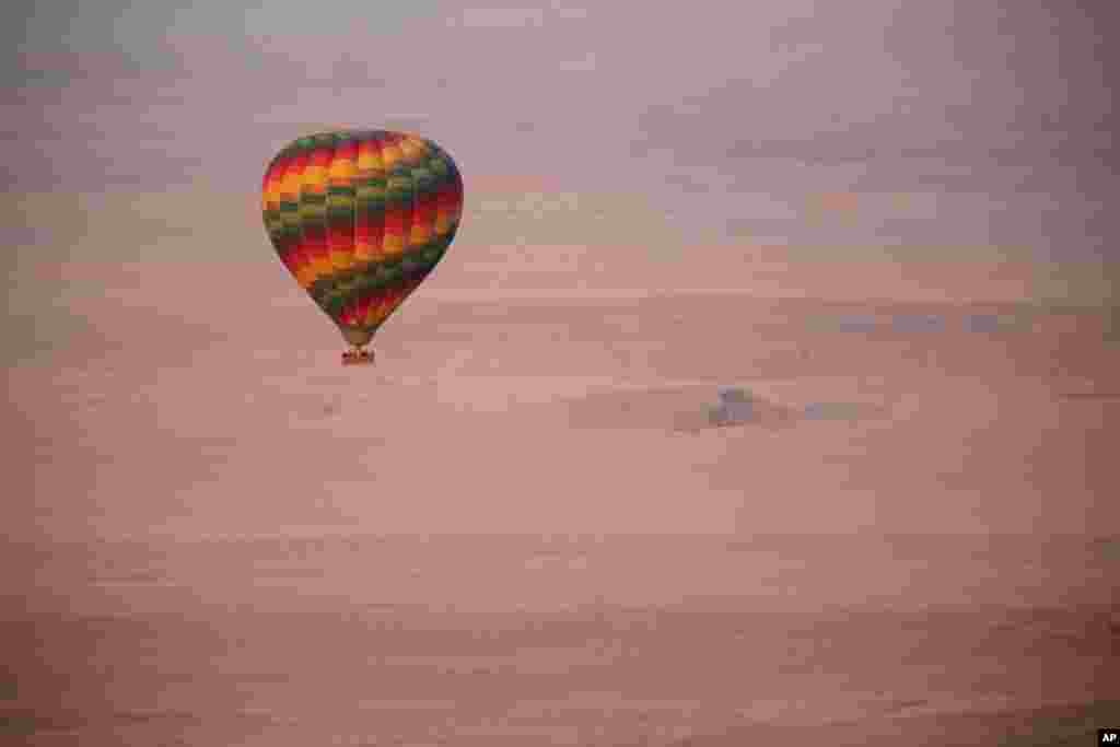 A hot air balloon flies over the desert near Luxor, Egypt. 