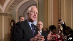 ARCHIVO- El Senador John Cornyn, R-Texas, flanqueado por el Senador John Thune, R-S.D., izquierda, y el líder de la mayoría senatorial Mitch McConnell, R-Ky., habla con reporteros sobre medidas de seguridad tras el ataque en una escuela en Parkland, Florida. 27-2-18.