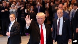 Le président élu Donald Trump salue la foule alors qu'il quitte les bureaux du New York Times après une réunion, le 22 novembre 2016, à New York.