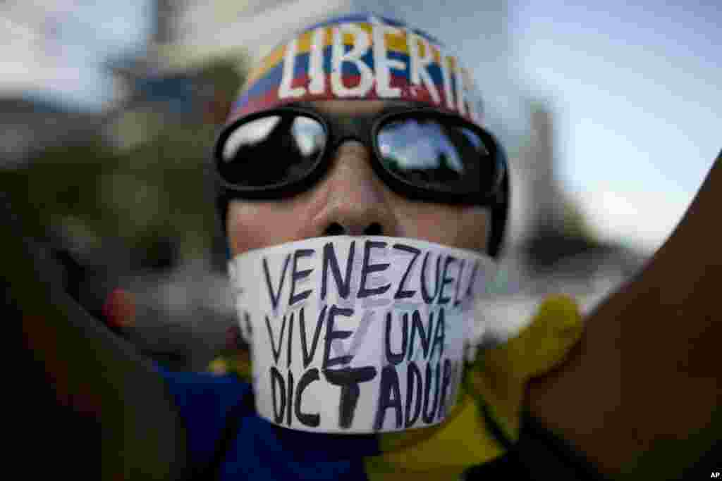 A woman wears a banner over her mouth with a message that reads in Spanish: "Venezuela lives in a dictatorship" during a protest, in Caracas, March 31, 2017. 