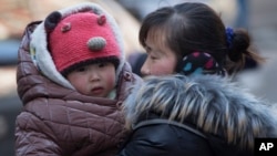 지난해 3월 중국 베이징에서 한 여성이 자녀를 안고 있다.