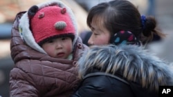 Seorang ibu menggendong anaknya di Beijing, China (foto: dok).