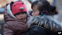 FILE - A Chinese woman cuddles her child in Beijing. China announced Thursday it was ending its long-standing one-child policy and will now allow all couples to have two children. (2014 AP PHOTO)