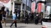 FILE - Plainclothes security personnel film as they gather to load detained worshippers onto a waiting bus near a building that leaders of the unregistered Shouwang house church had told parishioners to gather in Beijing, China, April 10, 2011.