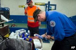A Transportation Security Adminstration (TSA) officer inspects a can which was packed in a suitcase flagged for a seconday inspection at Dulles International Airport in Dulles, Va., March 26, 2019.