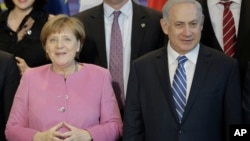 German Chancellor Angela Merkel, left, and the Prime Minister of Israel Benjamin Netanyahu, right, pose with government members for a group photo during a one day German-Israeli governmental meeting at the chancellery in Berlin, Germany, Feb. 16, 2016.