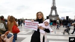 A woman holds her baby and a poster reading "Bring Back our Girls" during a rally to support the release of the kidnapped Nigerian girls at the Trocadero, in front of the Eiffel Tower, in Paris on May 13, 2014.