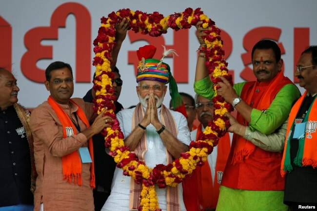 FILE - India's Prime Minister Narendra Modi gestures as he is presented with a garland during an election campaign rally in Himmatnagar, Gujarat, India, April 17, 2019.