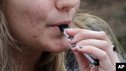 FILE - A high school student uses a vaping device near a school campus in Cambridge, Massachusetts, April 11, 2018.