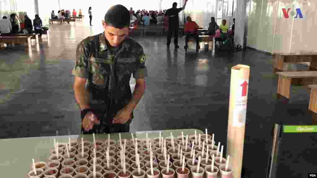Militar sirve comida en la mesa de un Centro de Recepción de Migrantes, administrado por ACNUR, en Pacaraima, Brasil. Foto: Celia Mendoza - VOA.