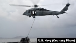 A MH-60S helicopter, from the “Island Knights” of Helicopter Sea Combat Squadron (HSC) 25, from the Military Sealift Command dry cargo and ammunition ship USNS Charles Drew (T AKE 10), transports a pallet of water en route to the Republic of the Philippin
