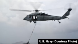 A MH-60S helicopter, from the “Island Knights” of Helicopter Sea Combat Squadron (HSC) 25, from the Military Sealift Command dry cargo and ammunition ship USNS Charles Drew (T AKE 10), transports a pallet of water en route to the Republic of the Philippines, Nov. 14, 2013.