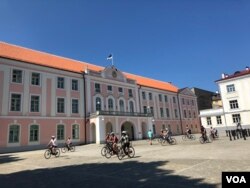 Bicyclists are seen in front of the Estonian Parliament building, Tallinn, Estonia, July 15, 2018. (S. Herman/VOA)