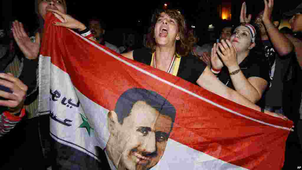 Les partisans du président syrien Bachar al-Assad tiennent un portrait d’Assad, agitent le drapeau de leur pays et manifestent leur solidarité à leur président, à Damas, en Syrie, 20 août 2011.