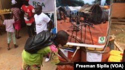 Un homme lave les mains avant d'entrer dans la salle d'exposition des ONG humanitaires le 19 août 2017 à Bangui. (VOA/Freeman Sipila)