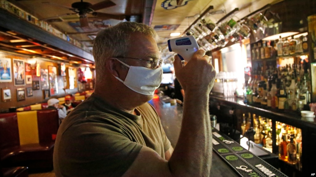 Cheers to You bar owner Bob Brown tests a thermometer at his bar Friday, May 1, 2020, in Salt Lake City. Brown realize he needs to hire two or three new people just to enforce social distancing guidelines. (AP Photo/Rick Bowmer)