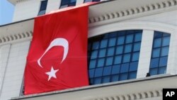 FILE - A Turkish flag is hung from the headquarters of Turkey's ruling Justice and Development party party, in Ankara, Turkey, March 20, 2013.