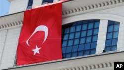 A Turkish flag is hung from the headquarters of Turkish Prime Minister Recep Tayyip Erdogan’s ruling party, apparently to conceal the damage after assailants fired a rocket on the building, in Ankara, March 20, 2013.