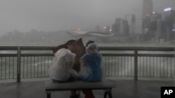 People play with strong wind caused by Typhoon Hato on the waterfront of Victoria Habour in Hong Kong, Aug. 23, 2017. The powerful typhoon barreled into Hong Kong Wednesday, forcing offices and schools to close and leaving flooded streets, shattered windo