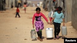 Internally displaced Syrian girls carry water containers in Jrzinaz camp in the southern part of Idlib, Syria, June 21, 2016.