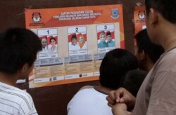 Para pemilih memperhatikan foto-foto kandidat pilkada di sebuah TPS di Tangerang, 9 Desember 2015. (Foto: AP)