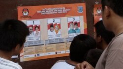 Para pemilih memperhatikan foto-foto kandidat pilkada di sebuah TPS di Tangerang, 9 Desember 2015.(foto: ilustrasi) Pilkada tahun ini penuh tantangan karena protokol kesehatan terkait pencegahan Covid-19.