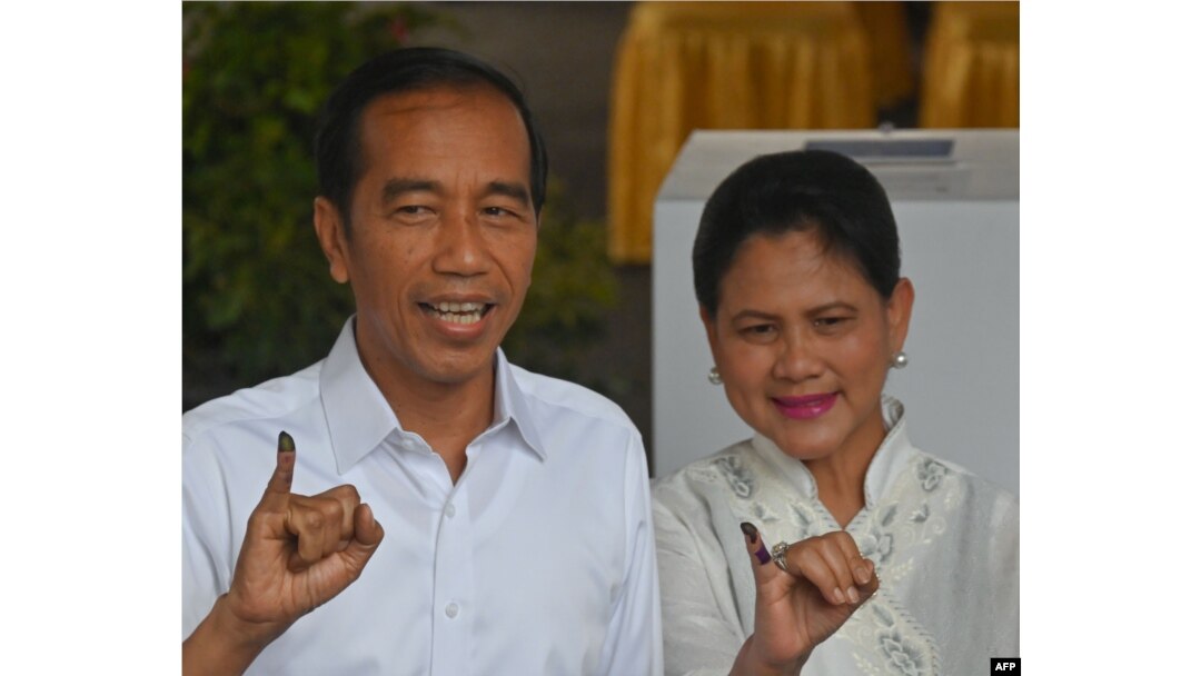 Incumbent President Joko Widodo and his wife, Iriana Widodo, display their inked fingers after casting their ballot at a polling center during the presidential and legislative election in Jakarta, April 17, 2019.