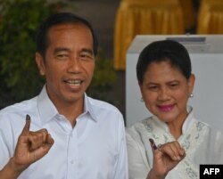 Incumbent President Joko Widodo and his wife, Iriana Widodo, display their inked fingers after casting their ballot at a polling center during the presidential and legislative election in Jakarta, April 17, 2019.