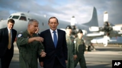 在珀斯附近，澳大利亚总理阿博特在空军指挥官陪同下从澳大利亚皇家空军一架P3-C猎户座飞机旁走过。（2014年3月31日）
