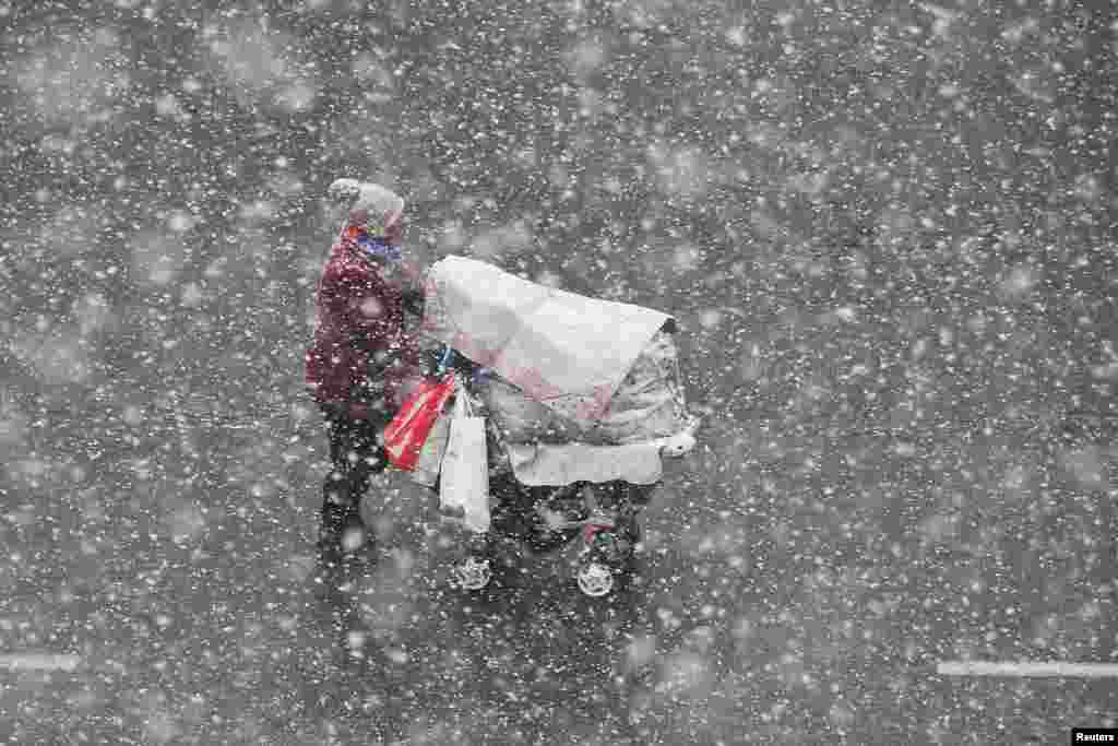 A woman pushing a stroller walks in the snow in Yantai, Shandong province, China.