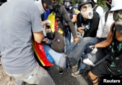 David Jose Vallenilla (C), who was fatally injured, is helped by fellow protesters outside an air force base during clashes with riot security forces at a rally against Venezuelan President Nicolas Maduro's government in Caracas, June 22, 2017.