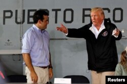 FILE - U.S. President Donald Trump talks with Puerto Rico Governor Ricardo Rossello (L) as they take their seats for a briefing on hurricane relief efforts in a hangar at Muniz Air National Guard Base in Carolina, Puerto Rico, Oct. 3, 2017.