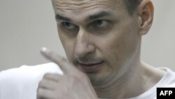 Ukrainian film director Oleg Sentsov looks out from a defendants' cage as he listens to the verdict at a military court in the southern city of Rostov-on-Don, Aug. 25, 2015.