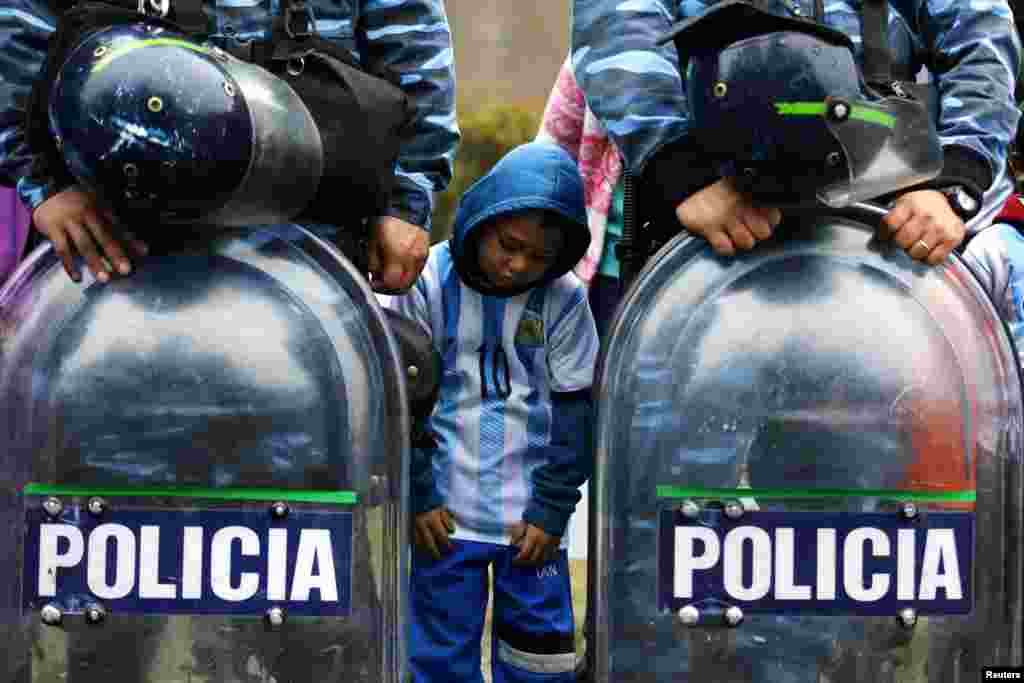 Một fan hâm mộ người Argentina đứng giữa cảnh sát khi họ tụ tập để chào đón đội bóng của họ bên ngoài Liên đoàn bóng đá Argentina tại thủ đô Buenos Aires sau khi Argentina thua Đức trong trận chung kết World Cup.