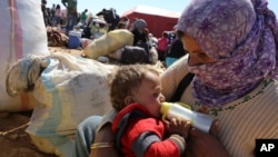 Người Syria tỵ nạn cho con uống sữa tại một cửa khẩu biên giới gần Suruc, Thổ Nhĩ Kỳ.
