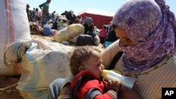 FILE - A Syrian refugee feeds her baby at a border crossing near Suruc, Turkey, Oct. 1, 2014.