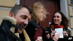 Aktivis Greenpeace, dari kiri: Philip Ball, Sini Saarela dan Alexandra Harris memperlihatkan paspor mereka yang mengijinkan mereka untuk meninggalkan Rusia kepada jurnalis di St. Petersburg, Rusia, 26/12/2013.