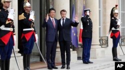 French President Emmanuel Macron, center right, and Japan's Prime Minister Shinzo Abe wave before their talks at the Elysee Palace, in Paris, April 23, 2019.