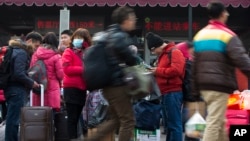Passengers carry their belongings while arriving at the Beijing railway station in Beijing, Jan. 19, 2014.