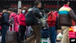 在北京火車站旅客們拉著行李戴著口罩抵達。 
