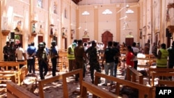 Sri Lankan security personnel walk through debris following an explosion in St Sebastian's Church in Negombo, north of the capital Colombo, on April 21, 2019.